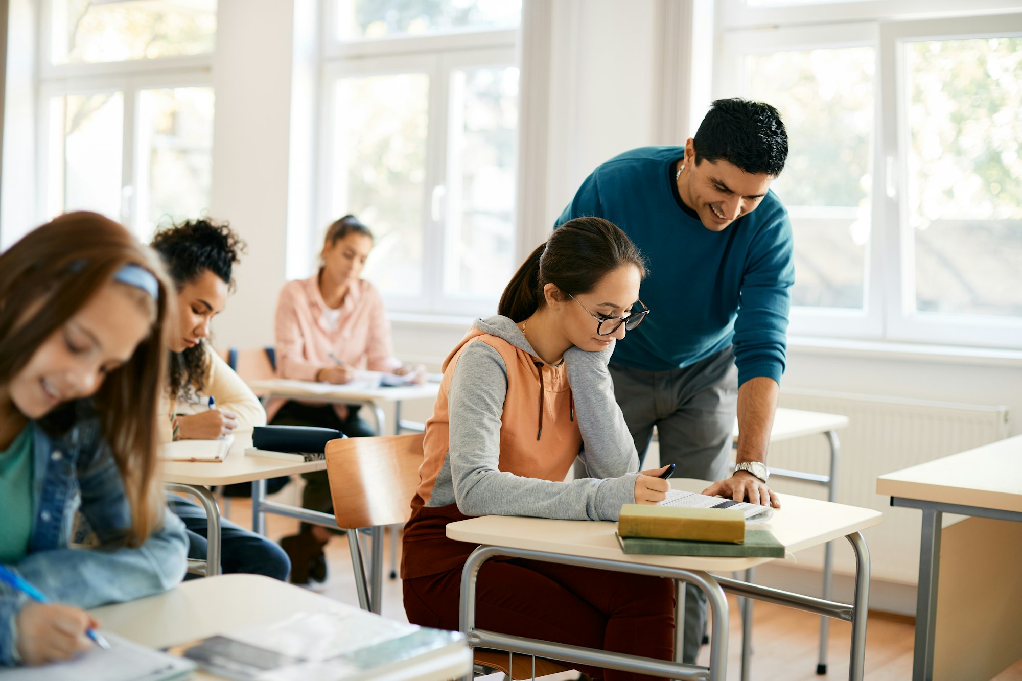 Female high school student leaning with teacher's help in the classroom.
